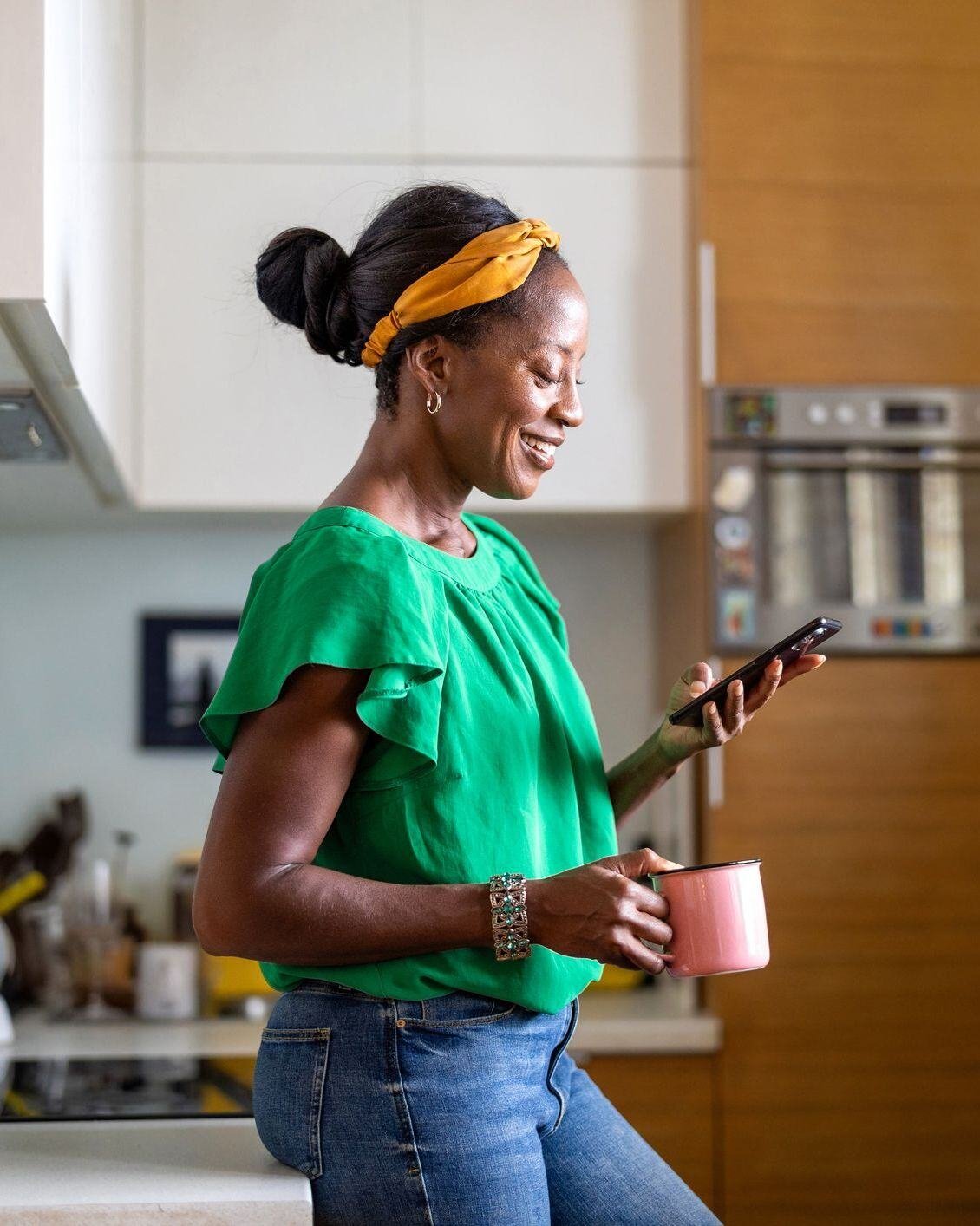 Woman holding coffee looking down on her phone